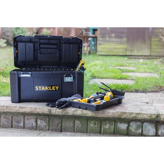 STANLEY STST1-75521 black toolbox open outdoors with yellow-handled tools and gloves on a stone step.