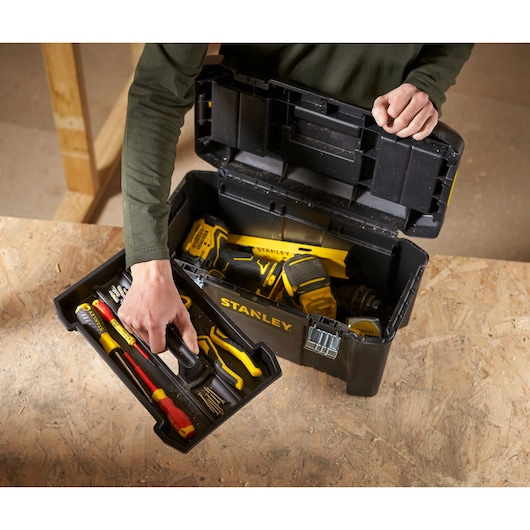 Stanley STST1-75521 toolbox with hand tools and a power drill, top view on a wooden surface.