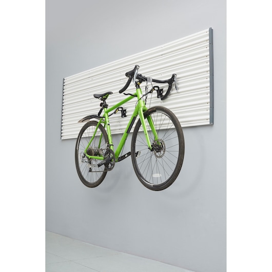 Photo of STANLEY STST82615-1 wall-mounted slat panel holding a green bicycle, side angle view.