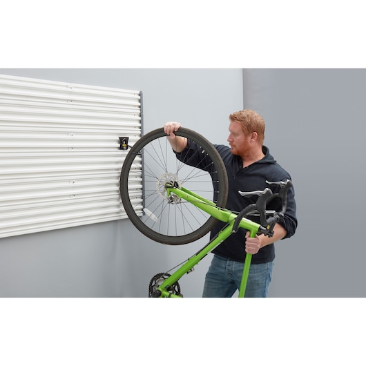 STANLEY STST82616-1 wall storage panel in white with a person mounting a green bicycle.
