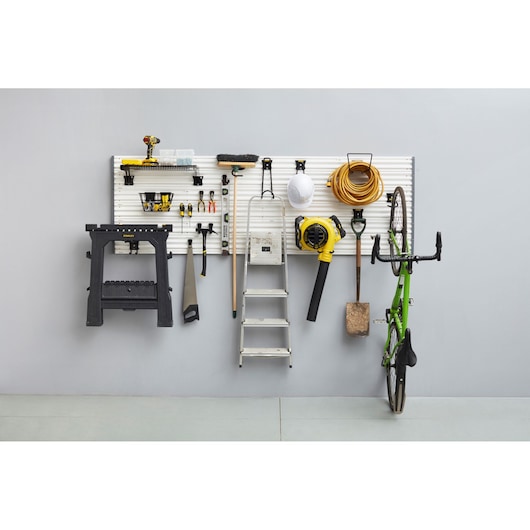STANLEY STST82616-1 wall-mounted tool organizer with various tools, step ladder, and bike, front view.