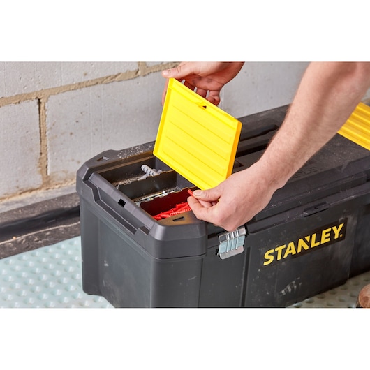 STANLEY STST82976-1 toolbox with yellow lid compartments, shown on floor with hand accessing interior.