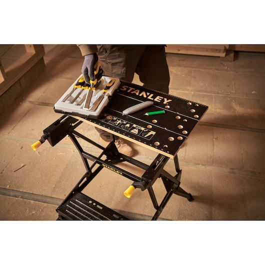 STANLEY STST83400-1 folding workbench with tools and accessories, top view in workshop setting.