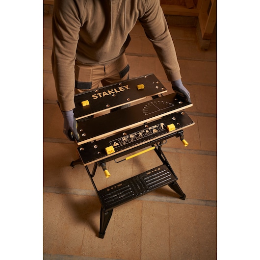 STANLEY STST83800-1 workbench with black tabletop and yellow adjustment knobs, angled from above.