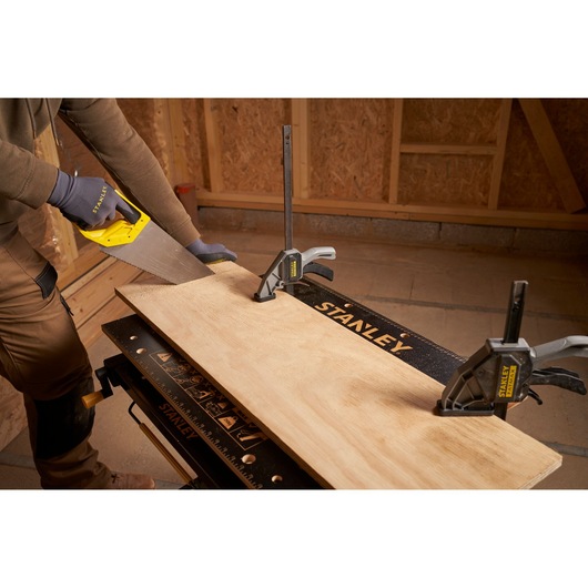Photo of STANLEY STST83800-1 clamps securing wood on workbench during sawing, product category: photography.