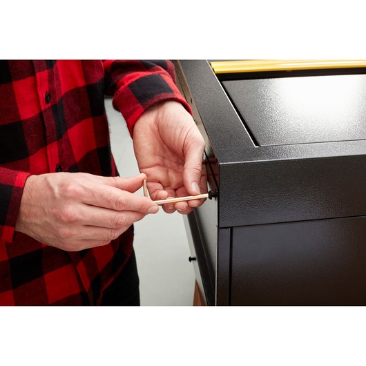 STANLEY STST97598-1 photography of person using hex key on black metal cabinet corner.