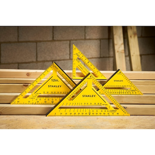 Photo of STANLEY STHT46013-0 yellow plastic carpenter squares on stacked lumber in workshop setting.