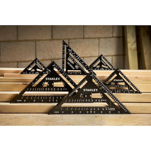 STANLEY STHT46105-0 photography of black triangular rafter squares in various sizes on wooden planks.