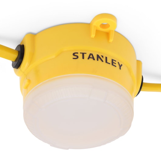 Close-up of a yellow Stanley LED work light with a round frosted cover and two cables attached.