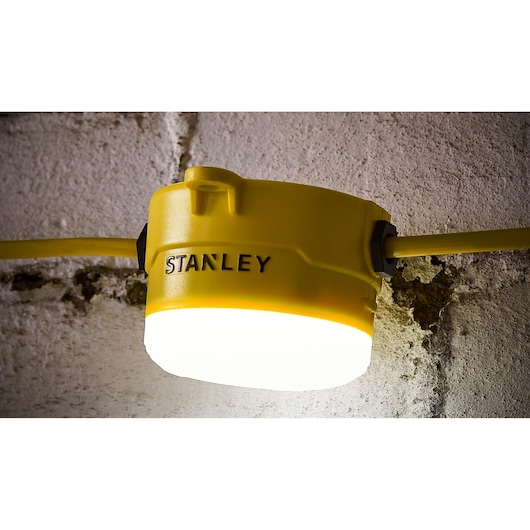 STANLEY SXLS31362E yellow work light mounted on wall, illuminated, product photography.