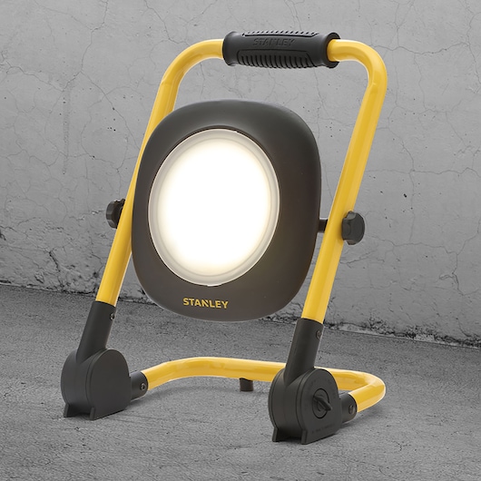 STANLEY SXLS35527E LED work light with yellow stand, front angle, on concrete floor.