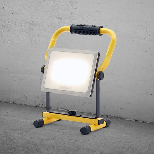 STANLEY SXLS36385E portable LED work light with yellow frame, front angle, on concrete floor.