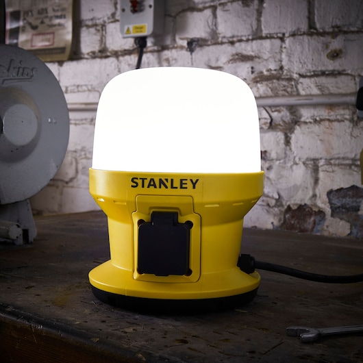 STANLEY SXLS36986E yellow LED work light on a workshop table, front angle.