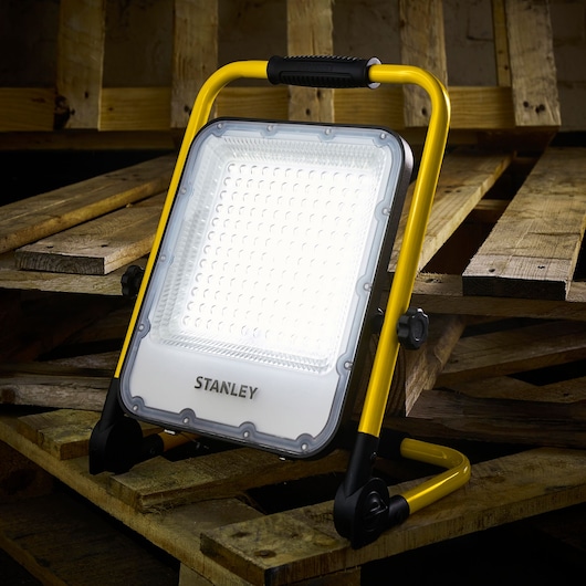 STANLEY SXLS37179E LED work light with yellow frame on wooden pallets, photography.