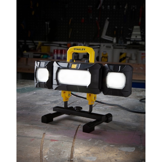 STANLEY SXLS37180E portable LED work light with yellow handle, standing on workshop table.
