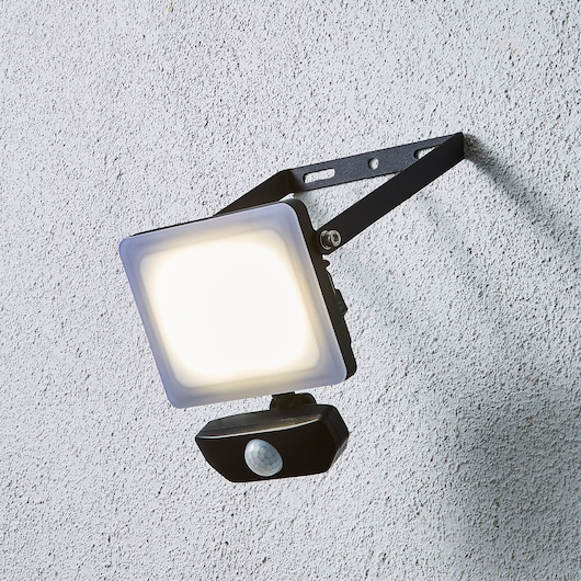 STANLEY SXLS38934E LED floodlight with motion sensor, wall-mounted, side view, black bracket.