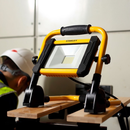 STANLEY SXLS41220E LED work light, yellow and black, front angle, mounted on wooden surface.