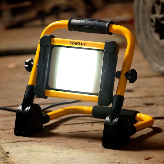 STANLEY SXLS41220E portable LED work light with yellow frame, photographed on a workshop floor.