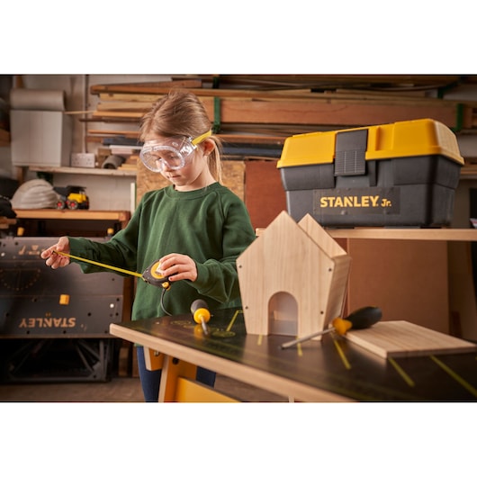 STANLEY TBS001-05-SY toolbox with yellow lid and woodworking tools in workshop setting.