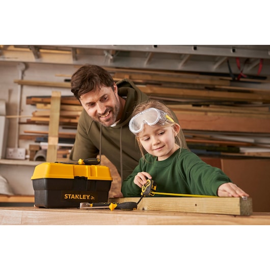 STANLEY TBS001-05-SY toolbox and tools with tape measure in woodworking workshop, side angle.